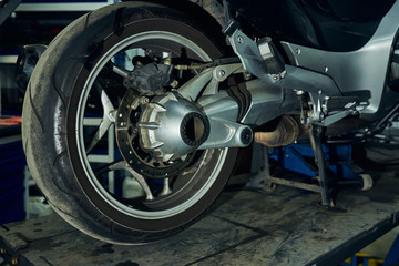 View of the rear wheel of a motorcycle in a motorcycle workshop.