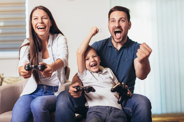 Smiling family sitting on the couch together playing video games