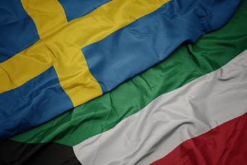 waving colorful flag of kuwait and national flag of sweden.