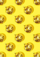 New year baubles. Shiny gold disco balls on yellow background. Pop disco style attributes, retro concept. Creative Christmas pattern. Flat lay, top view.