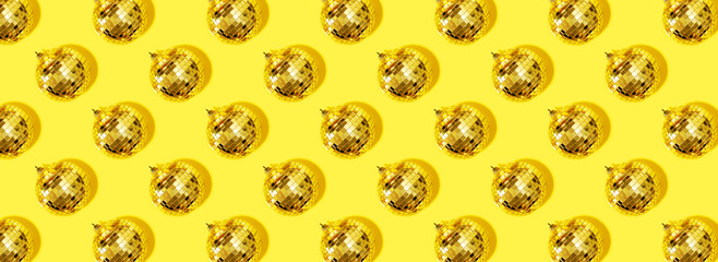 Fototapeta na wymiar Christmas gold baubles organized on yellow background. Top view. Flat lay. Creative New year pattern. Party time concept. Banner