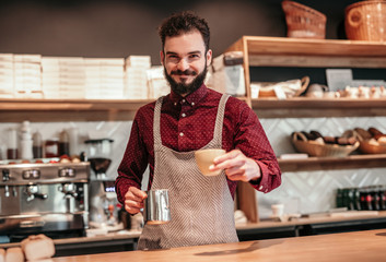 Stylish hipster barista making cup of coffee in cafe