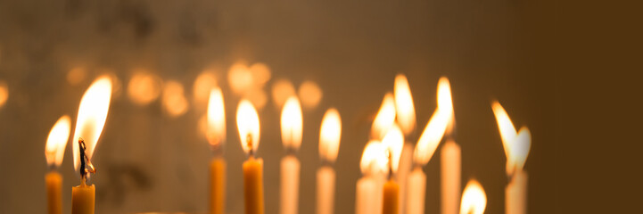 Close up of candles in a church, panoramic christmas and holiday lights, funeral or grief background