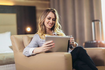 Young attractive businesswoman in hotel room using digital tablet.