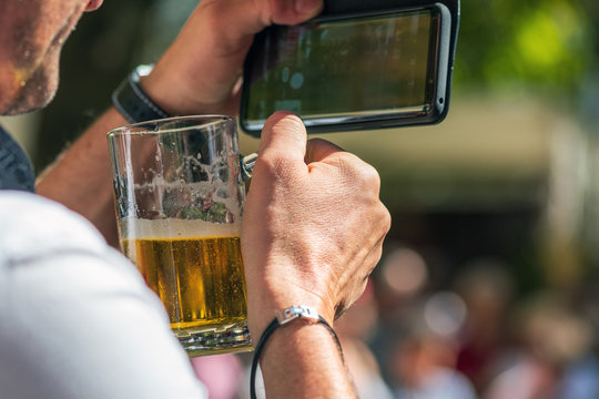 Mann mit Bier fotografiert etwas mit dem Handy