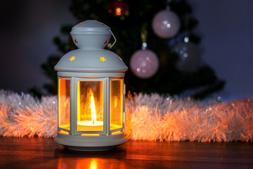Decorative lantern with candle under Christmas tree at night_
