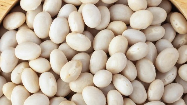 panning heap of white beans in wood bowl isolated on white background