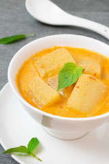 Coconut milk curry with winter melon in white bowl on table.
