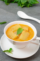 Coconut milk curry with winter melon in white bowl on table.