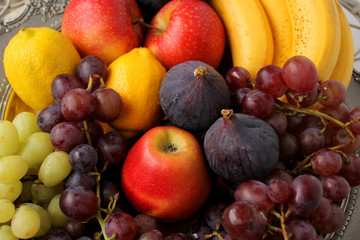 beautiful fruits, apples, plums, lemons, bananas, purple figs, clusters of black and green grapes with drops, splashes of water, close-up, vitamins concept, vegan food, healthy eating, copy space