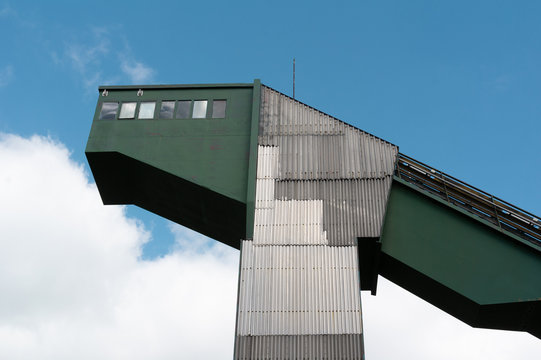 Detail of building of ski jump in Frenstat pod Radhostem. Old aged retro and vintage building is made of corrugated iron. Angular building with diagonal shape. Blue sky with clouds in the background.
