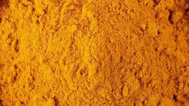 panning turmeric powder in wood bowl isolated on white background