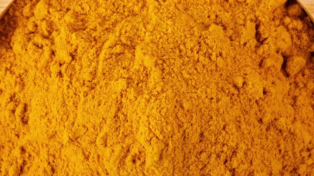 panning turmeric powder in wood bowl isolated on white background