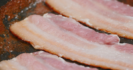 Fry bacon in pan in kitchen for breakfast