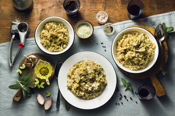 Classic Italian risotto with mushrooms on a wooden table with a blue linen tablecloth. red wine. bottle and glasses. top shots