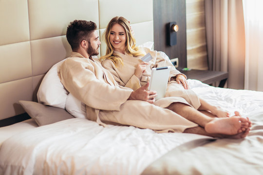 Young happy couple shopping online in luxury hotel room.