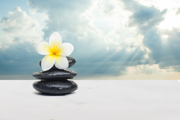 Obraz na płótnie Canvas Tropical yellow flower and stones on white background. Spa healt