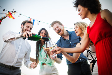 Group of happy friends partying and toasting drinks