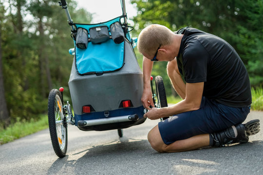 Young man with in line skates fixes broken buggy baby stroller