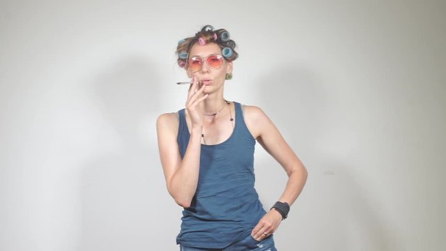 housewife with glasses and curlers smokes a jamb with marijuana in the toilet