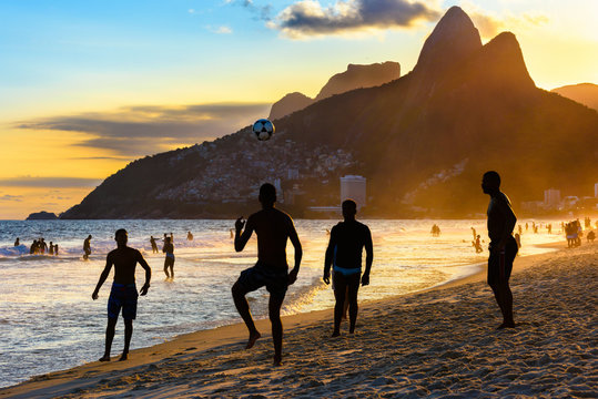 Brazilian boys play football on Ipanema beach at sunset in Rio de Janeiro, Brazil.
