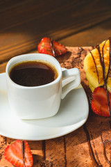 Pancakes with strawberries chocolate and coffee on a wooden table
