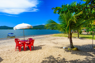 Jabaquara beach with umbrella and chairs in Paraty, Rio de Janeiro, Brazil. Paraty is a preserved Portuguese colonial and Brazilian Imperial municipality