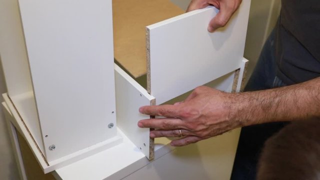 a man assembling white furniture