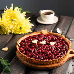 cherry tart with heart shaped decor, on a dark wooden backdrop, golden daisy and cup of coffee on background