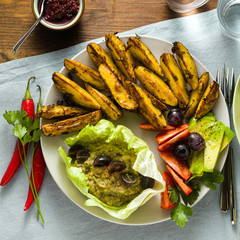 whole plant vegan lunch or dinner of baked potatoes, baba ganoush, tomato and avocado salad. modern healthy food. shot from above.
