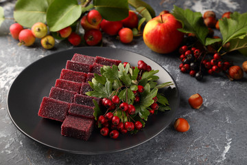 Sweet marmalade made from apples and hawthorn fruits, with the addition of aronia juice, beautifully laid out on a black plate.