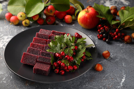 Sweet marmalade made from apples and hawthorn fruits, with the addition of aronia juice, beautifully laid out on a black plate.