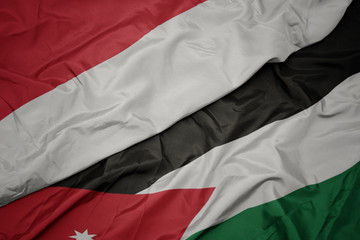 waving colorful flag of jordan and national flag of indonesia.