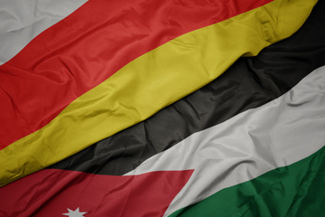 waving colorful flag of jordan and national flag of south ossetia.