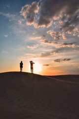 Fototapeta na wymiar Silhouettes of man and woman on top of a sand dune in the Sahara desert