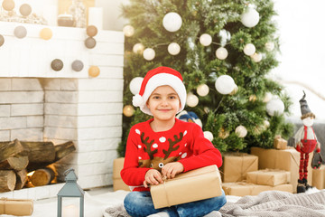 Obraz na płótnie Canvas Happy little boy opening Christmas gifts near New Year's tree