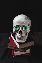 Creepy cranium with funny toy eyes on pile of books