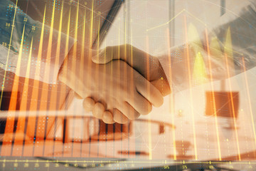 Multi exposure of financial graph on office background with two businessmen handshake. Concept of success in business