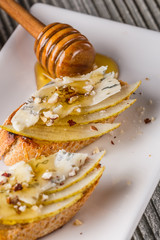 Appetizer bruschetta with pear, honey, walnut and blue cheese on white plate