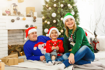 The charming family sitting near Christmas Tree