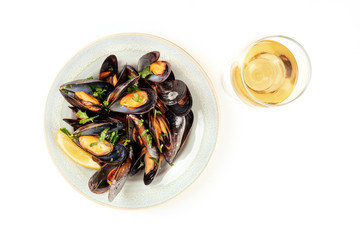 Marinara mussels, moules mariniere, shot from the top on a white background with a glass of wine and copy space
