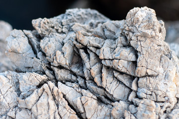 Raw stone on the coast of the Aegean. Texture of weathered, cracked stone. Gray with black veins.