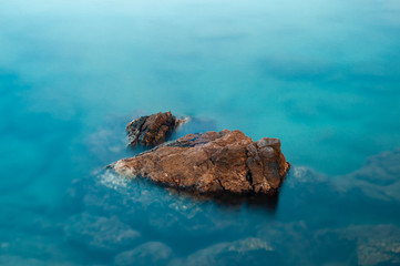 Stone in a turquoise, blue sea. Beautiful seascape at long exposure. Aegean coast in Turkey at sunrise. Bodrum.