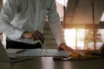 professional architect, engineer or interior hands drawing with divider compass and blueprint on workplace desk in office center at construction site, construction, engineering and business concept