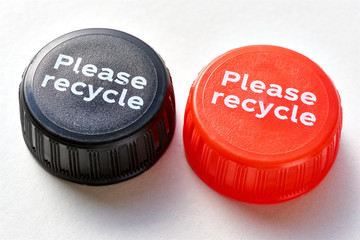 Black and red bottle cap with please recycle message against a white background. Concept of plastic pollution. 