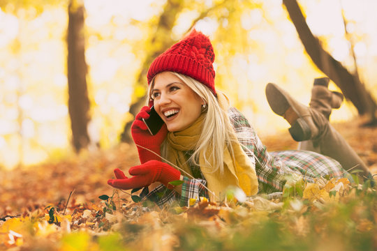 trendy young woman in autumn park having call on her smartphone