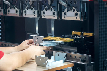 Operation of hydraulic bending machine with forming die by skill operator, The sheet metal manufacturing process by bending machine with technician operator.