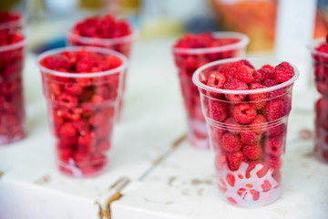 Fresh raspberry in plastic glasses for sale in market