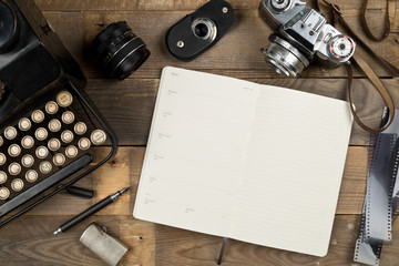 Vintage retro typewriter, analog film camera and open notebook on brown wooden table background top view flat lay from above - journalism or writer concept - Powered by Adobe