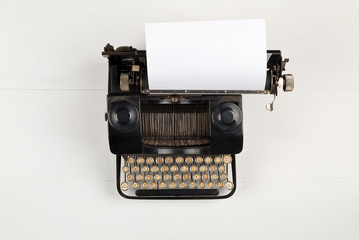 Vintage retro typewriter with sheet of paper on white table background top view flat lay from above...